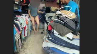 The shopkeeper observes as I try on clothes in his store