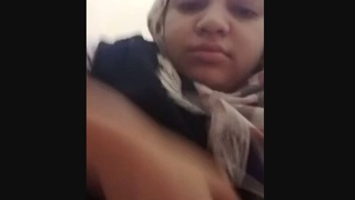 A Pakistani woman confidently displays her large breasts in a public setting